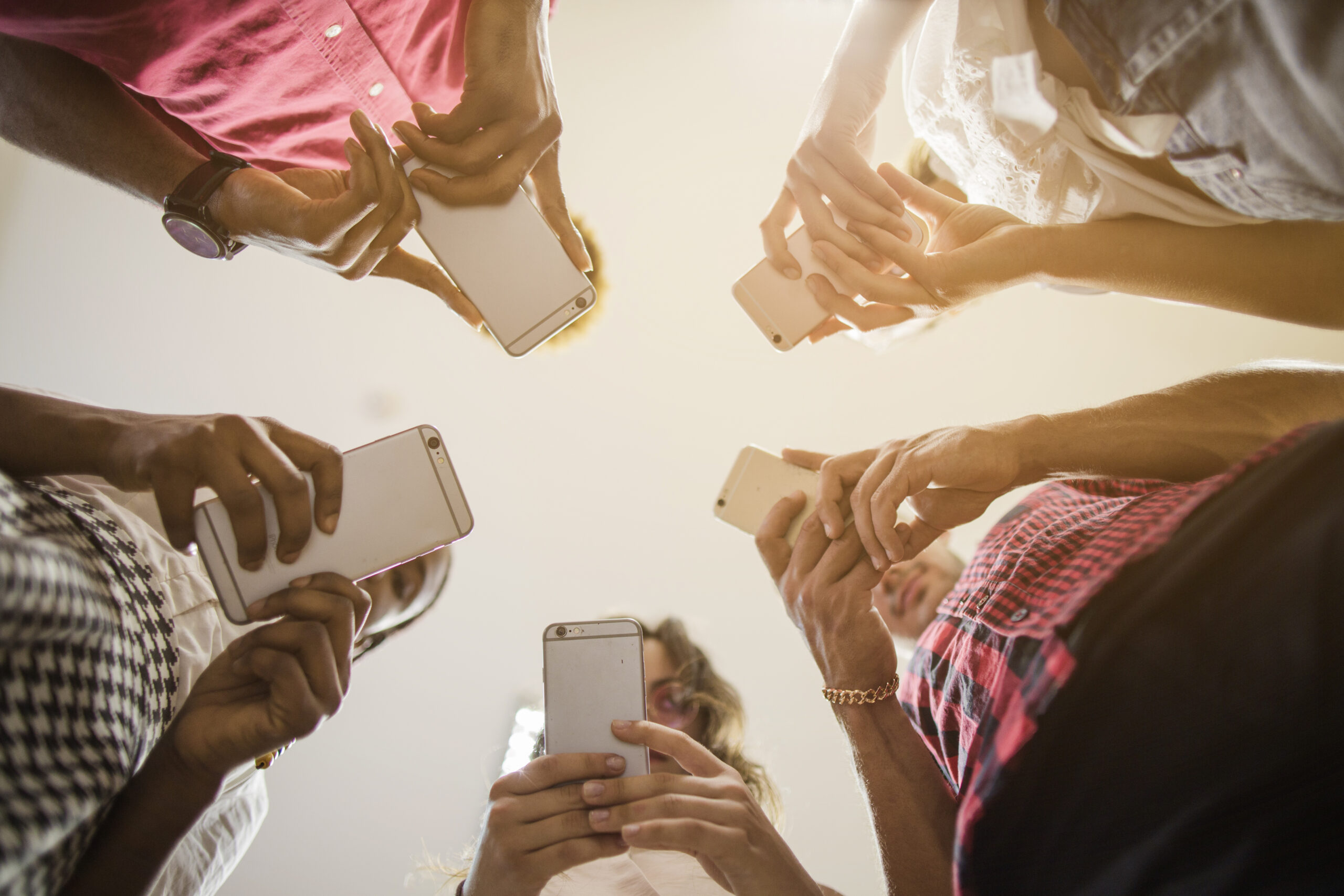 ludzie stojące w kręgu, patrzący na ekrany telefonów